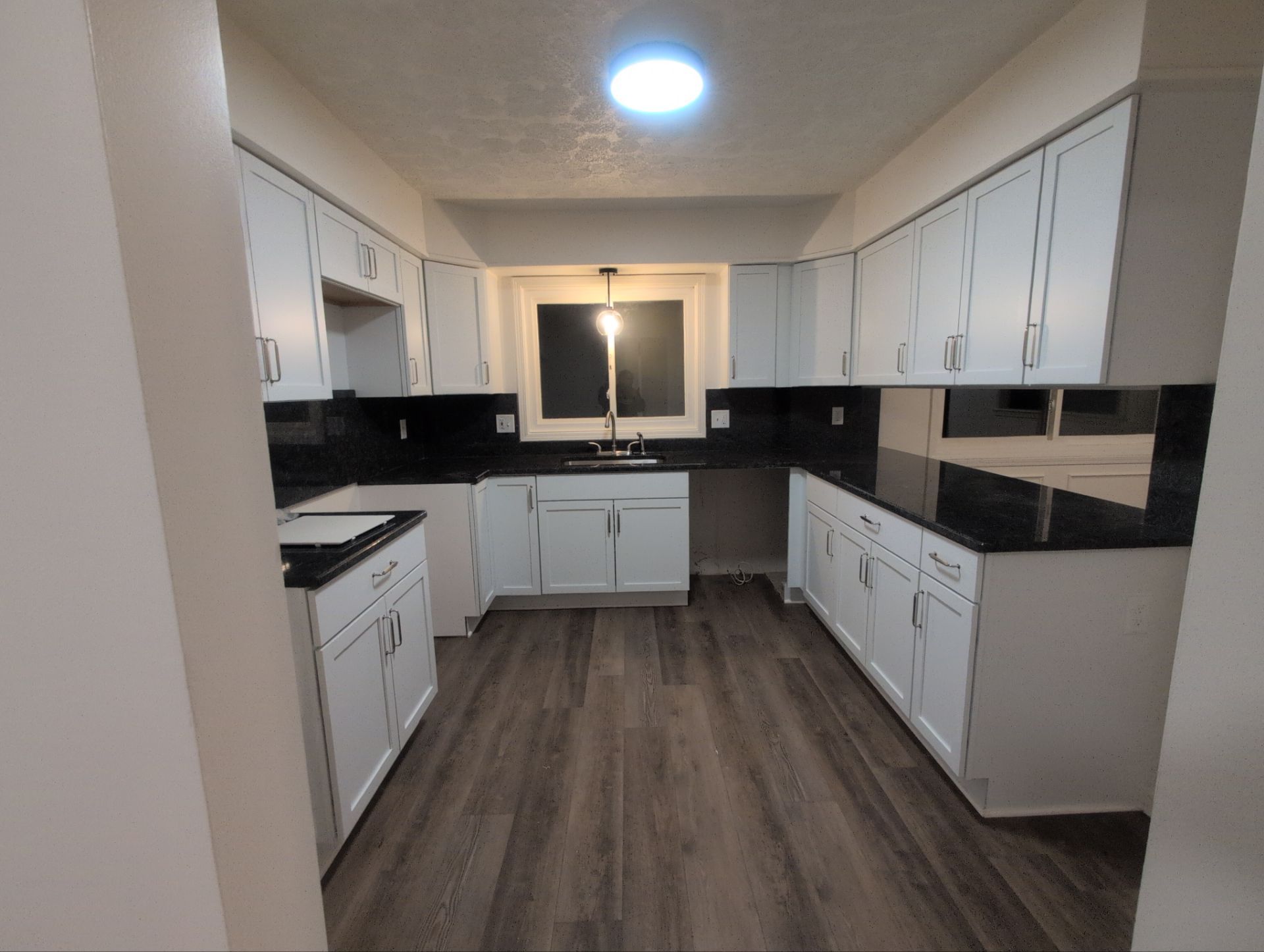 Finished kitchen with white cabinetry, dark counters, and updated flooring